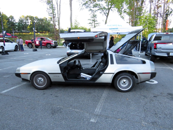 A silver DeLorean with its doors open.
