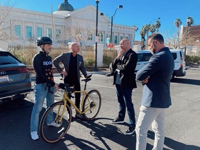 Four men in a group with a bicycle talking about C-V2X technology